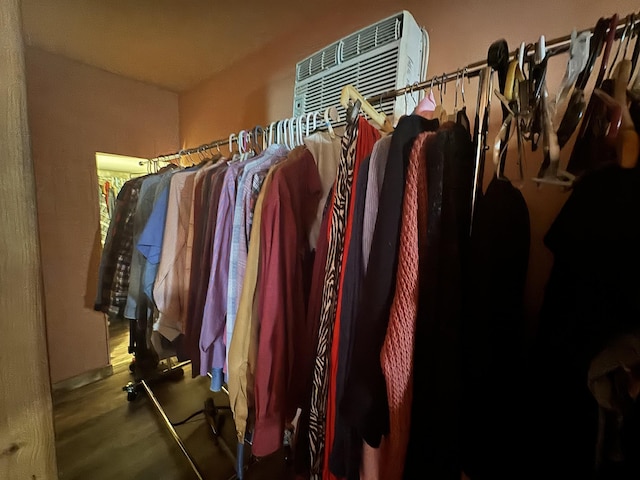 walk in closet with an AC wall unit and hardwood / wood-style flooring