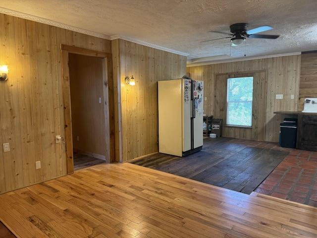 unfurnished room featuring ceiling fan, dark hardwood / wood-style floors, wood walls, crown molding, and a textured ceiling