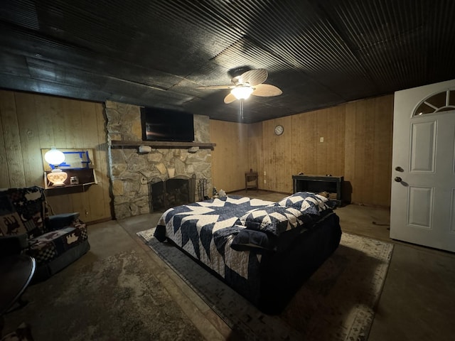 bedroom featuring ceiling fan, wood walls, and a fireplace