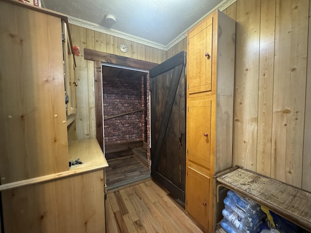 mudroom featuring light hardwood / wood-style flooring, crown molding, and wood walls