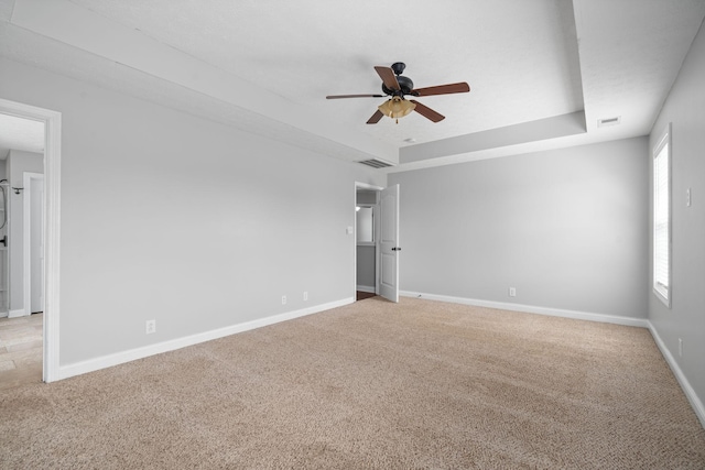 carpeted spare room featuring a tray ceiling and ceiling fan