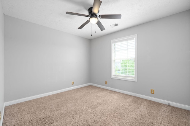 spare room with a textured ceiling, carpet floors, and ceiling fan