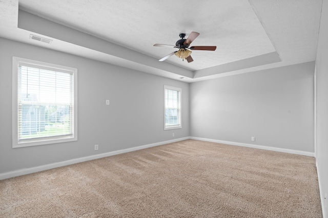 spare room with carpet, a textured ceiling, a raised ceiling, and ceiling fan