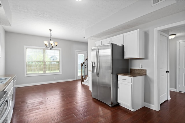 kitchen featuring dark wood-type flooring, stainless steel appliances, a chandelier, a textured ceiling, and white cabinets