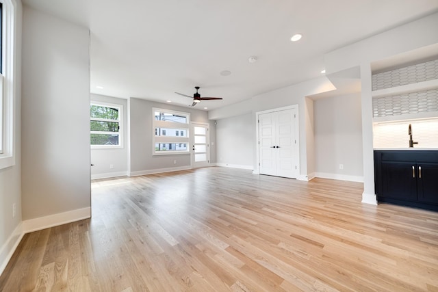 unfurnished living room featuring ceiling fan, sink, and light hardwood / wood-style flooring