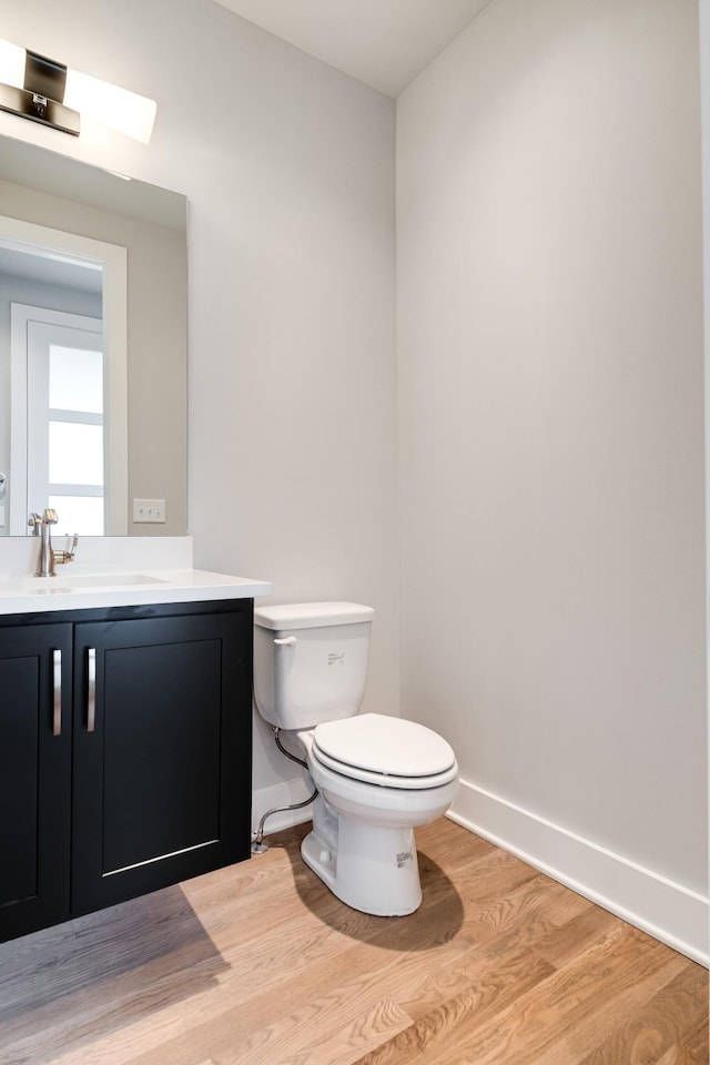 bathroom with a skylight, vanity, wood-type flooring, and toilet