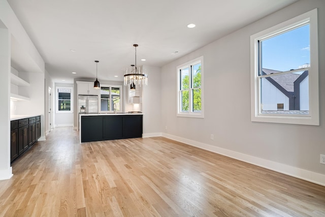 kitchen with pendant lighting, a notable chandelier, white cabinets, stainless steel fridge with ice dispenser, and light hardwood / wood-style floors