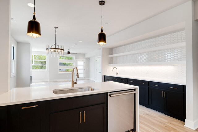 kitchen with decorative backsplash, sink, pendant lighting, dishwasher, and light hardwood / wood-style floors