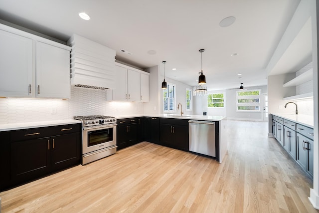 kitchen with sink, stainless steel appliances, pendant lighting, white cabinets, and custom exhaust hood