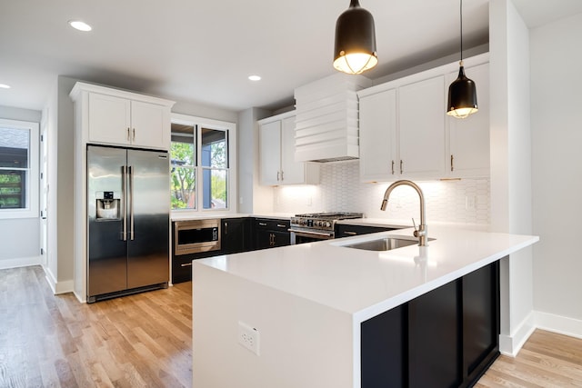 kitchen featuring sink, pendant lighting, light hardwood / wood-style flooring, high quality appliances, and white cabinets