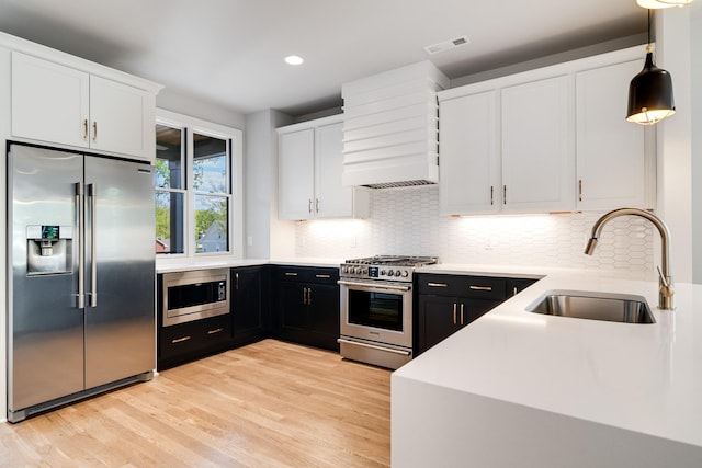 kitchen featuring decorative light fixtures, white cabinetry, high quality appliances, and sink