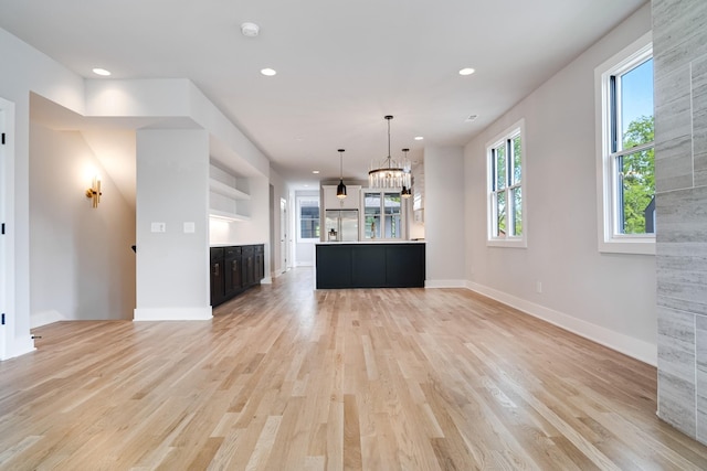 unfurnished living room featuring light hardwood / wood-style floors and an inviting chandelier