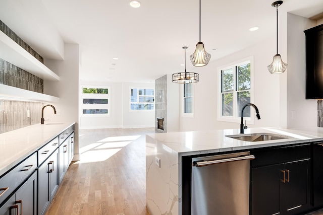 kitchen with pendant lighting, light hardwood / wood-style floors, light stone countertops, and sink