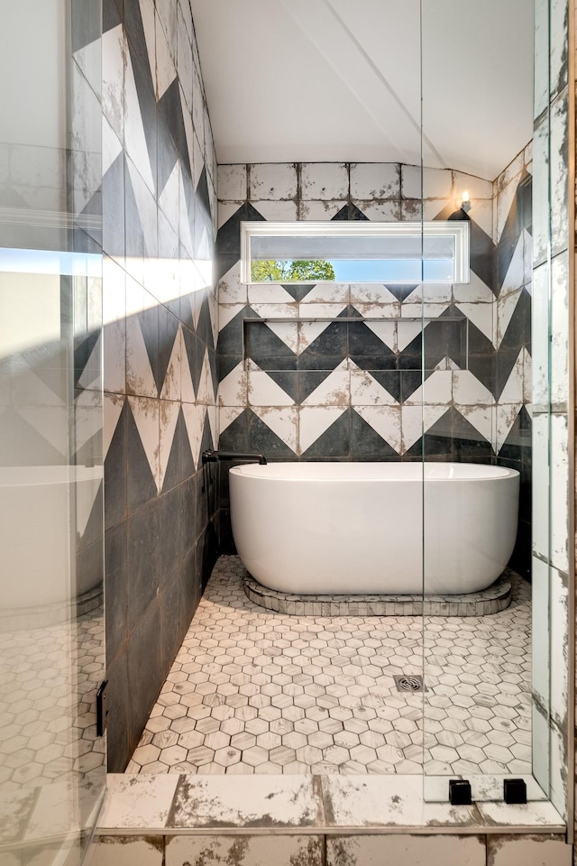 bathroom with a tub to relax in and tile walls