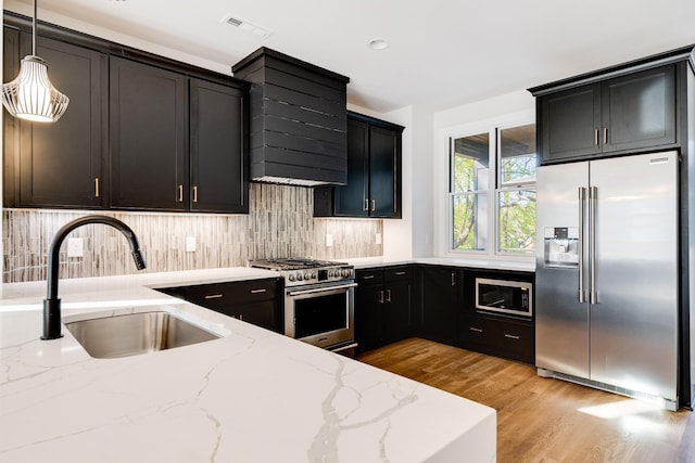 kitchen with sink, hanging light fixtures, stainless steel appliances, light stone counters, and backsplash