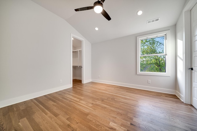 unfurnished bedroom featuring a spacious closet, ceiling fan, lofted ceiling, and light wood-type flooring