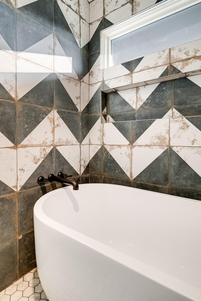 bathroom with a tub to relax in, tile patterned floors, and tile walls