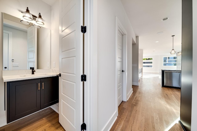 corridor with light wood-type flooring and sink