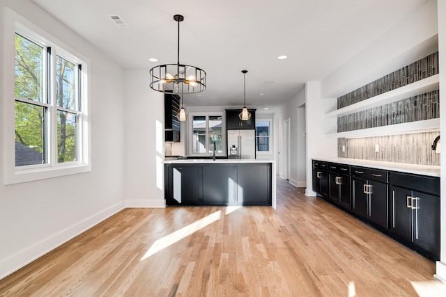 kitchen featuring an inviting chandelier, sink, hanging light fixtures, light hardwood / wood-style floors, and stainless steel fridge with ice dispenser