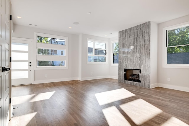 unfurnished living room with hardwood / wood-style flooring, a fireplace, and a wealth of natural light