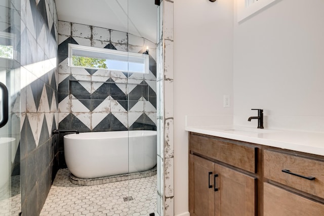 bathroom with a washtub, vanity, tile patterned floors, and tile walls