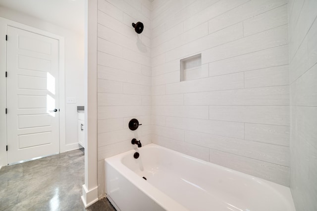 bathroom with concrete floors and tiled shower / bath