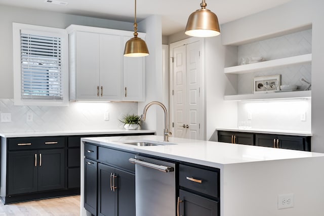 kitchen with sink, hanging light fixtures, white cabinets, light hardwood / wood-style floors, and a kitchen island