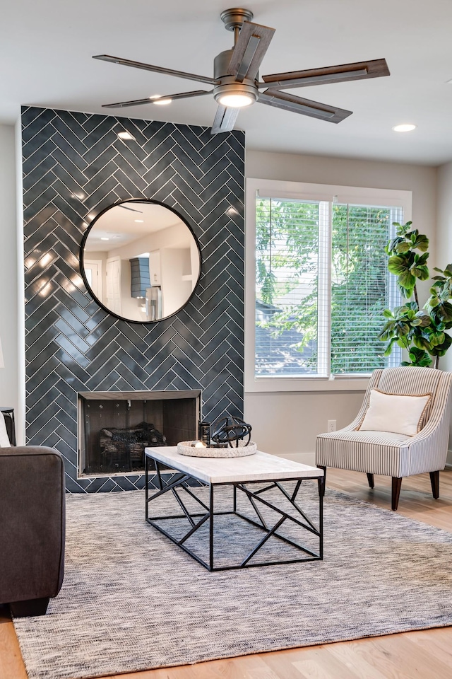 living room featuring a tile fireplace, ceiling fan, and hardwood / wood-style flooring