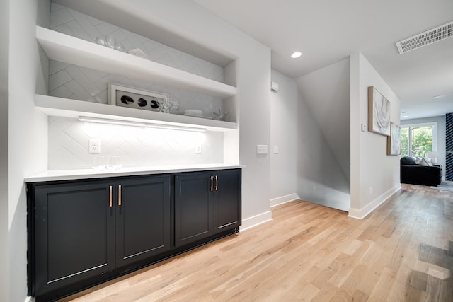 bar with backsplash and light hardwood / wood-style flooring