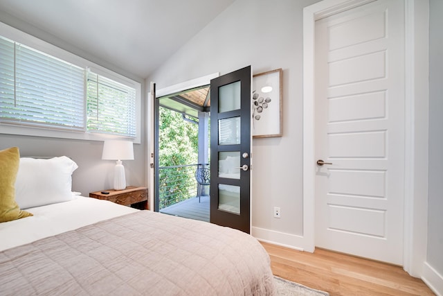 bedroom with access to exterior, hardwood / wood-style floors, and vaulted ceiling