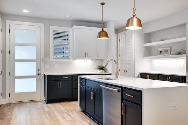 kitchen with white cabinetry, sink, an island with sink, light hardwood / wood-style floors, and decorative light fixtures