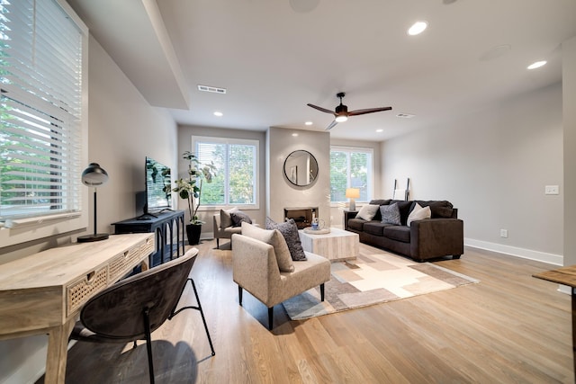 living room with ceiling fan, light hardwood / wood-style floors, and a fireplace