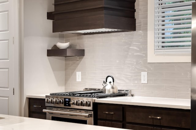 kitchen featuring dark brown cabinetry, decorative backsplash, double oven range, and custom range hood