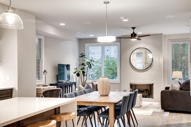 dining room featuring ceiling fan, a fireplace, and light hardwood / wood-style flooring