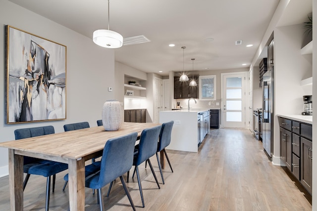 dining room with built in features, sink, and light hardwood / wood-style flooring