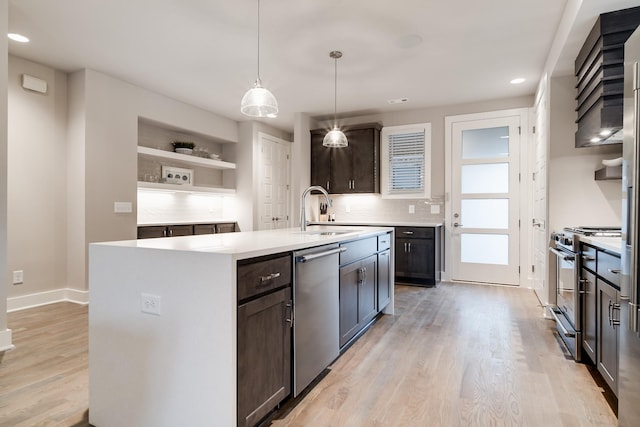 kitchen featuring dark brown cabinets, stainless steel appliances, sink, a center island with sink, and hanging light fixtures