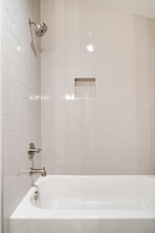 bathroom with tiled shower / bath combo and lofted ceiling