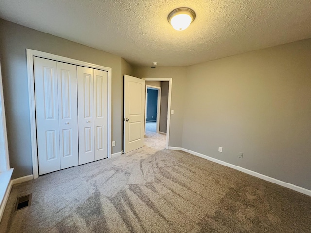 unfurnished bedroom with light colored carpet, a textured ceiling, and a closet