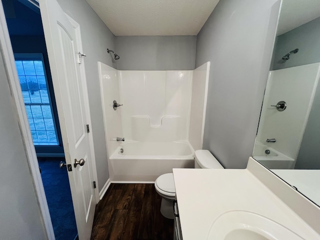 full bathroom featuring vanity, bathtub / shower combination, hardwood / wood-style flooring, toilet, and a textured ceiling