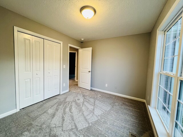 unfurnished bedroom with light colored carpet, a textured ceiling, and a closet