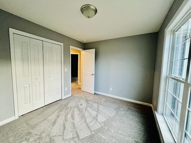 unfurnished bedroom featuring light colored carpet and a closet