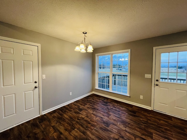 entrance foyer featuring a textured ceiling, a water view, dark wood-type flooring, and a notable chandelier