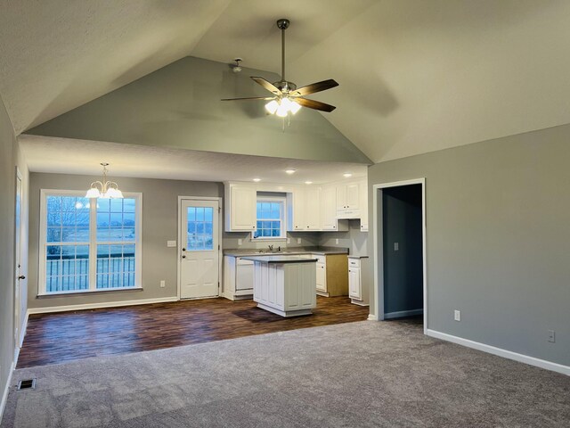 kitchen with white cabinets, ceiling fan with notable chandelier, vaulted ceiling, a kitchen island, and dark hardwood / wood-style flooring