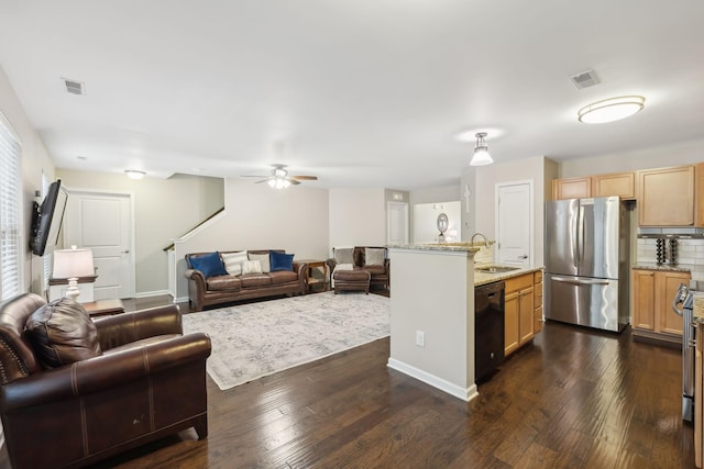 kitchen with dark hardwood / wood-style flooring, light stone counters, sink, black dishwasher, and stainless steel refrigerator