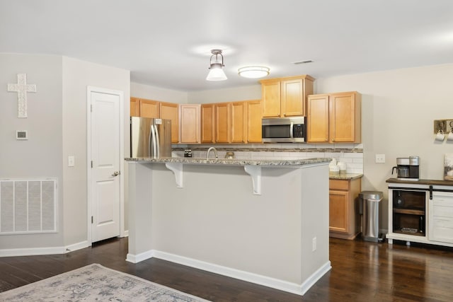 kitchen with light stone countertops, decorative backsplash, stainless steel appliances, dark hardwood / wood-style floors, and a breakfast bar area