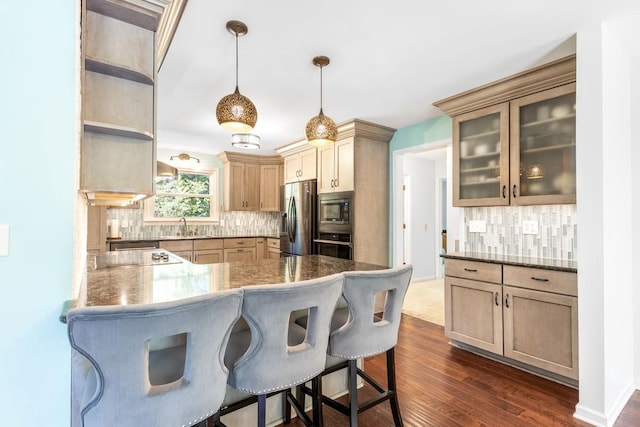 kitchen with dark wood-type flooring, hanging light fixtures, appliances with stainless steel finishes, tasteful backsplash, and kitchen peninsula