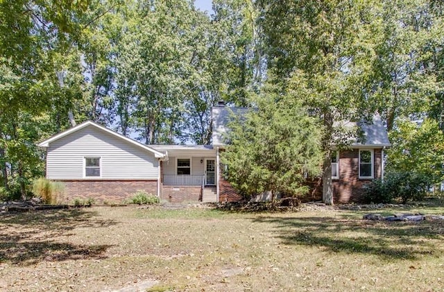 rear view of house with covered porch and a yard