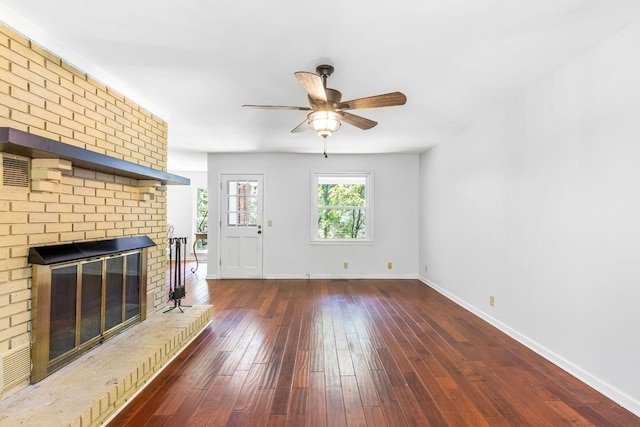 unfurnished living room featuring ceiling fan, dark hardwood / wood-style flooring, and a brick fireplace