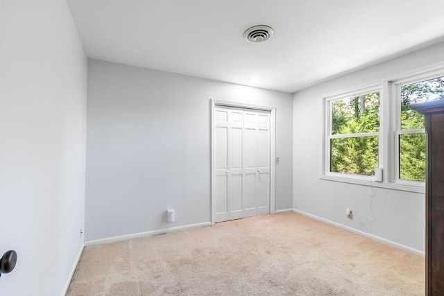 unfurnished bedroom featuring light colored carpet and a closet