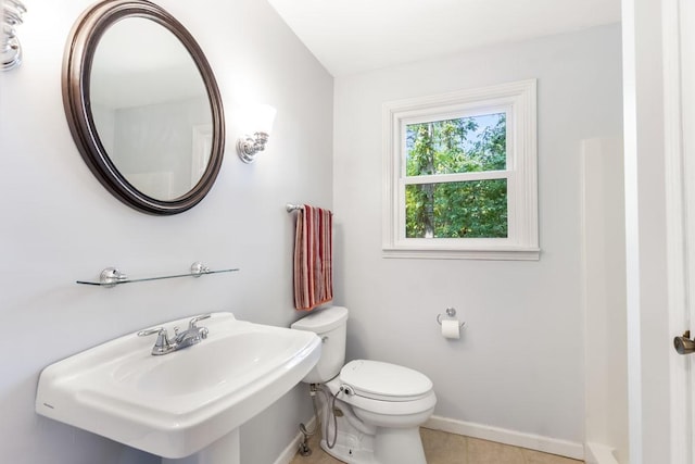 bathroom with toilet, sink, and tile patterned flooring